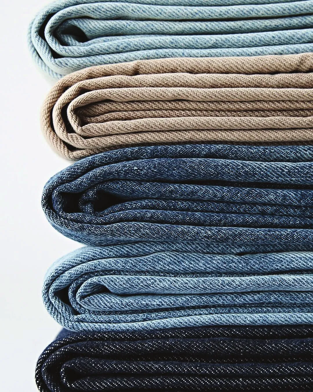 Folded jeans stacked from light wash to dark rinse